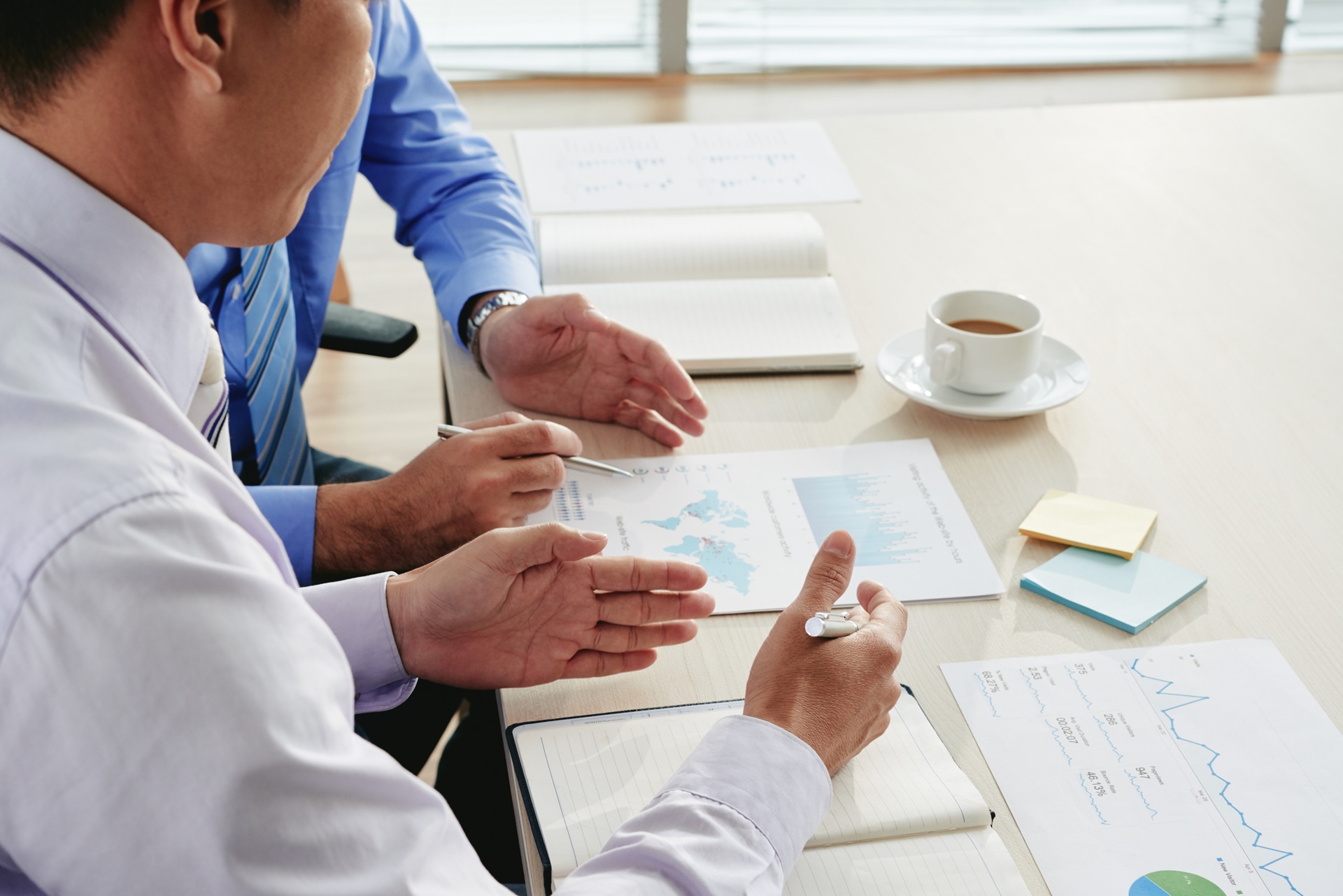 Hands of coworkers discussing chart at meeting